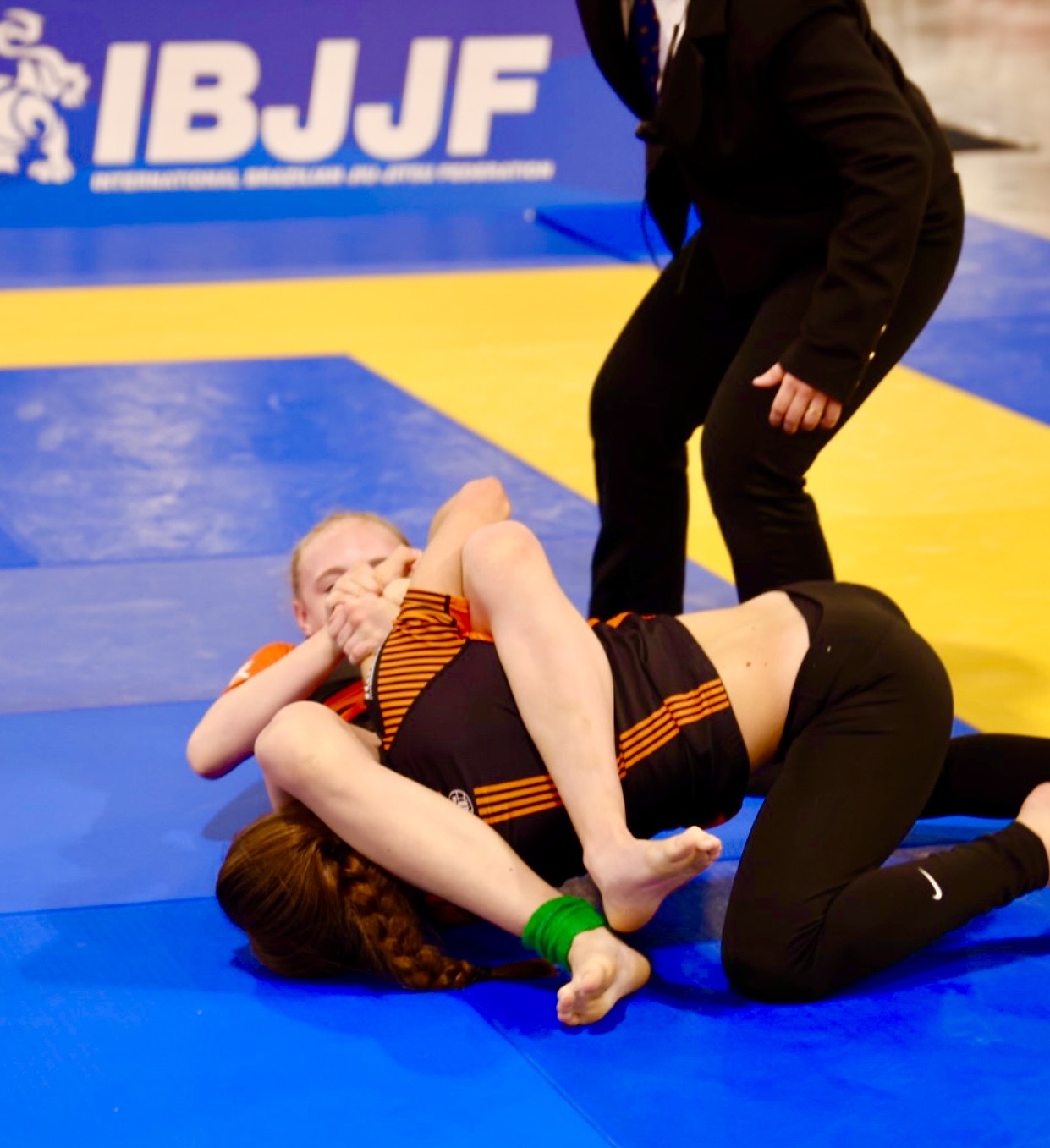 Imagen adicional de competencia del cuadro del Pan Kids IBJJF No-Gi Championship 2024. Se muestra a la protagonista en una transición de control a sumisión. Identidad gráfica de la IBJJF visible en el fondo del tapete de competencia.